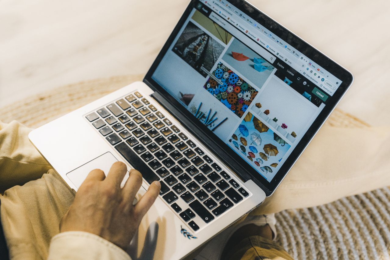 our-story A person using a laptop to browse stock photo websites. Freelancing work in a cozy setting.