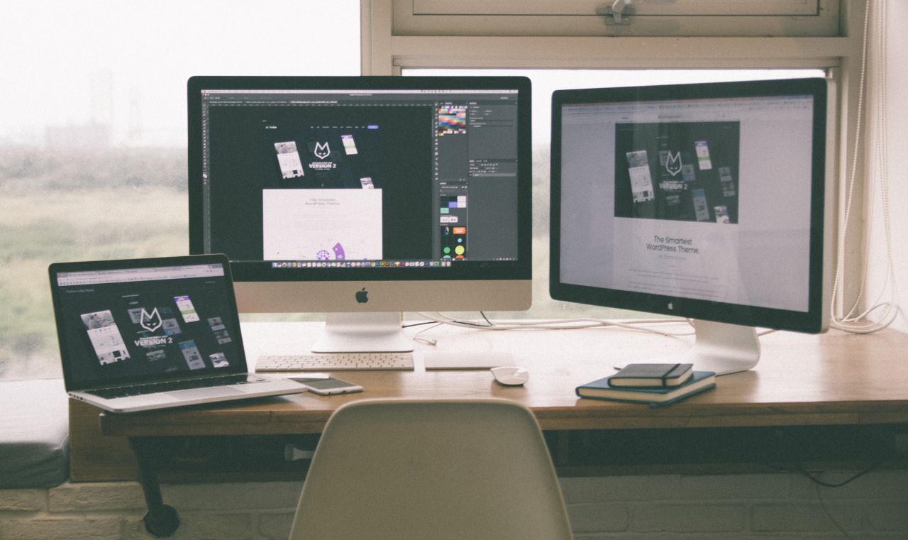 creativo Espacio de trabajo elegante y eficiente con varios monitores, una laptop y un smartphone, mostrando un proyecto de diseño web.